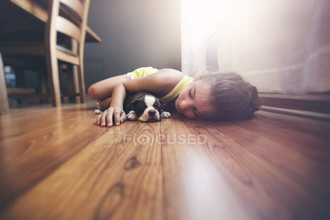 Fille couchée sur le sol avec un chiot Boston Terrier endormi — Photo de stock