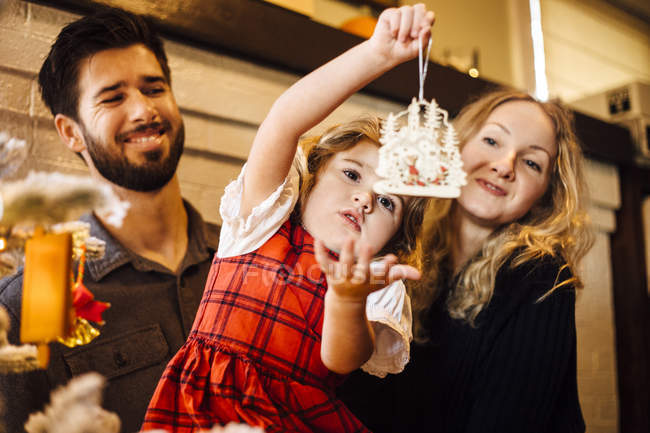 Female toddler with parents gazing at christmas decoration — Stock Photo