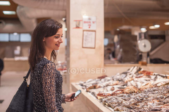 Frau schaut sich frischen Fisch auf Markt an — Stockfoto
