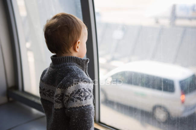 Garçon regardant par la fenêtre de l'aéroport — Photo de stock