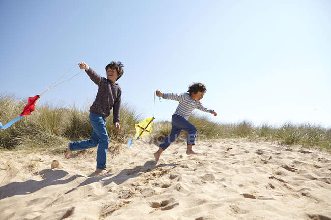 Двоє молодих хлопчиків, літаючі повітряні змії на пляжі — стокове фото