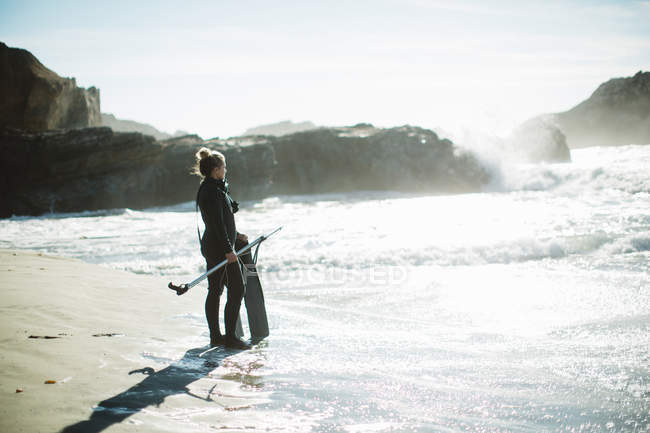 Diver with speargun on beach, Big Sur, California, USA — Stock Photo