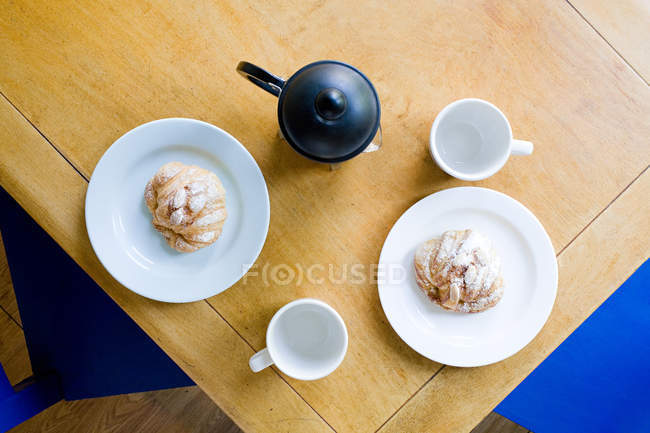 Tetera y croissants en platos - foto de stock