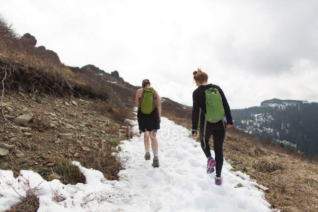 Zwei junge Frauen wandern am Berghang entlang, Rückansicht, Silver Star Mountain, Washington, USA — Stockfoto
