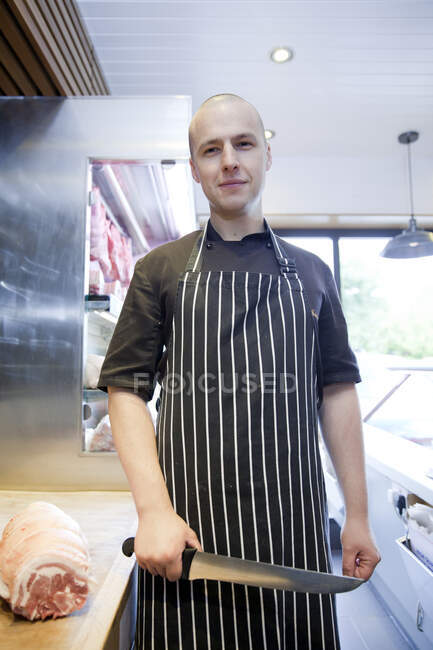 Portrait of butcher holding butchers knife in butchers shop — Stock Photo