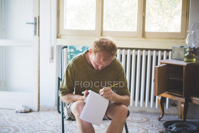 Чоловік пише нотатки в кімнаті — стокове фото