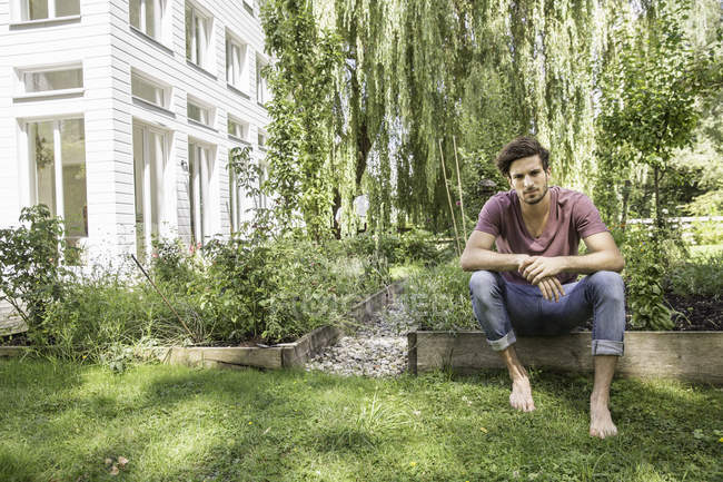 Молодой человек сидит в саду — стоковое фото
