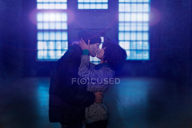 Casal beijando em armazém vazio — Fotografia de Stock