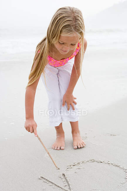 Fille écrit sur le sable — Photo de stock