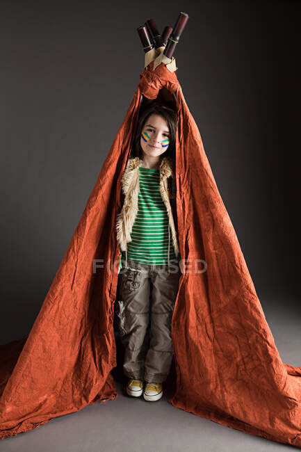 Young boy dressed up in Native American outfit, with teepee — Stock Photo
