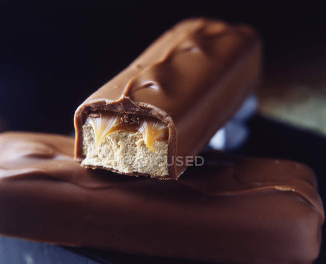 Dos barras de chocolate con leche apilada con relleno de caramelo y turrón - foto de stock