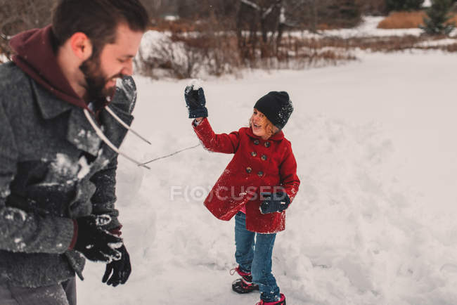 Ragazza che lancia palla di neve a suo padre — Foto stock