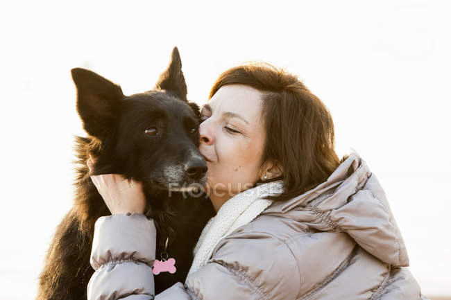 Primer plano de la mujer adulta media besando a su perro - foto de stock
