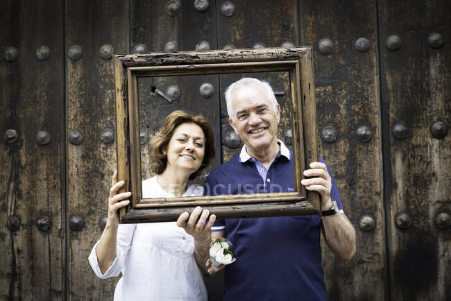 Portrait of senior couple, holding wooden frame in front of their faces, Mexico City, Mexico — Stock Photo
