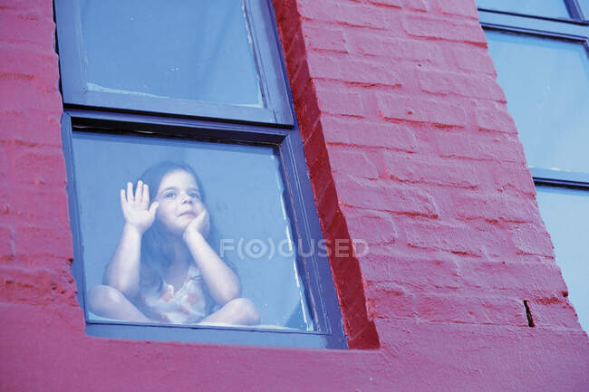Ragazza guardando attraverso la finestra — Foto stock
