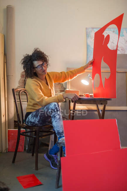 Artist cutting out red cardboard — Stock Photo