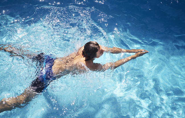 Вид сверху на молодого человека, плавающего в бассейне — стоковое фото