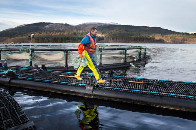 Lavoratore nell'allevamento di salmoni nel lago rurale — Foto stock