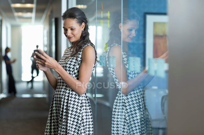 Бизнесмен, использующая мобильный телефон в офисе — стоковое фото