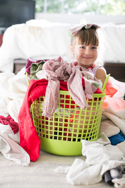 Girl sitting in basket among laundry — Stock Photo
