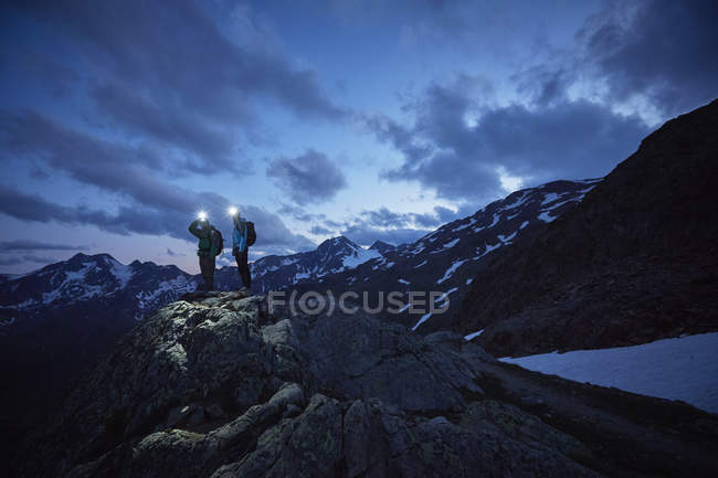 Pareja de senderismo joven con vistas a las montañas escarpadas por la noche, Glaciar Val Senales, Val Senales, Tirol del Sur, Italia - foto de stock