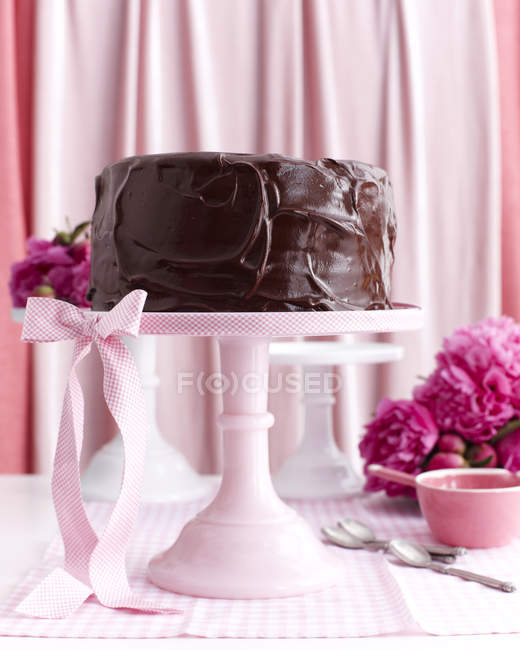 Chocolate layer cake on pink stand — Stock Photo