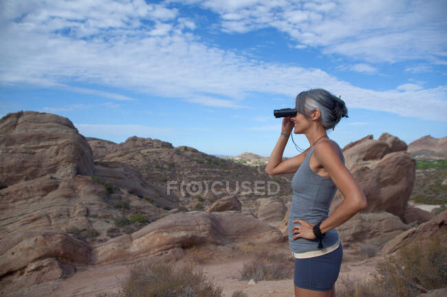 Woman standing at Vazquez Rocks looking through binoculars — Stock Photo