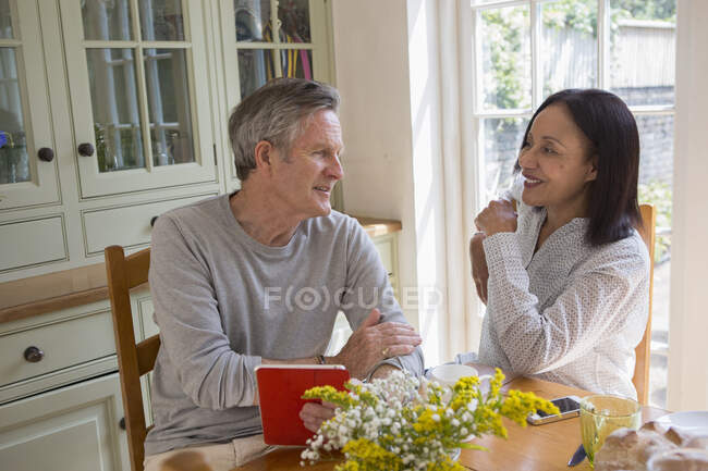 Старшая пара на кухне, смотрит на цифровой планшет — стоковое фото