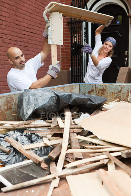 Couple filling skip with rubble — Stock Photo