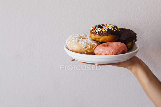 Рука тримає тарілку з пончиками — стокове фото