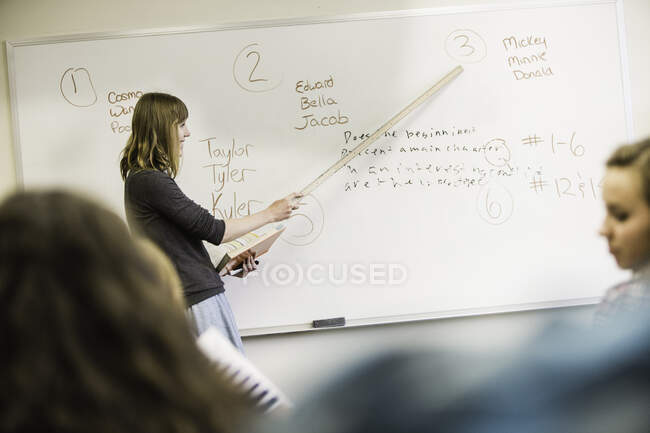 Lehrerin zeigt in High-School-Stunde auf Whiteboard — Stockfoto