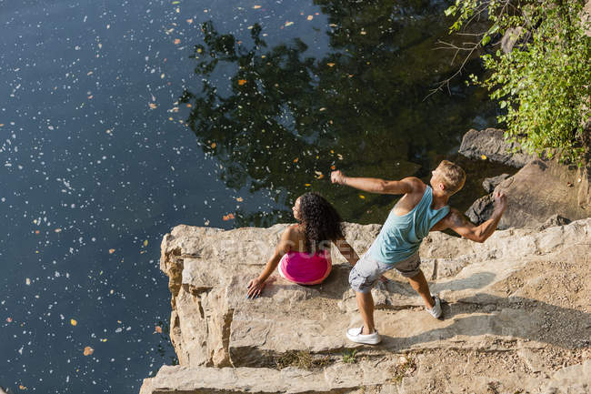 Young couple throwing stones from rock ledge, Hamburg, Pennsylvania, USA — Stock Photo