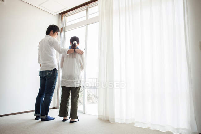 Casal em pé à janela — Fotografia de Stock