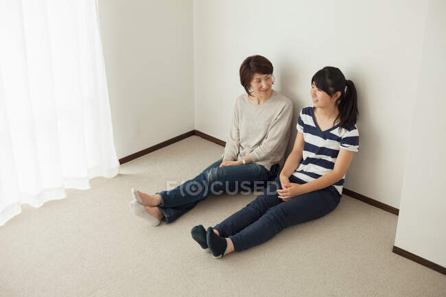 Mãe e filha adolescente sentadas no chão, retrato — Fotografia de Stock