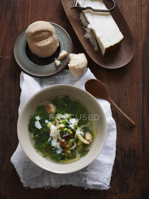 Top view of soup bowl with bread roll and parmesan cheese — Stock Photo