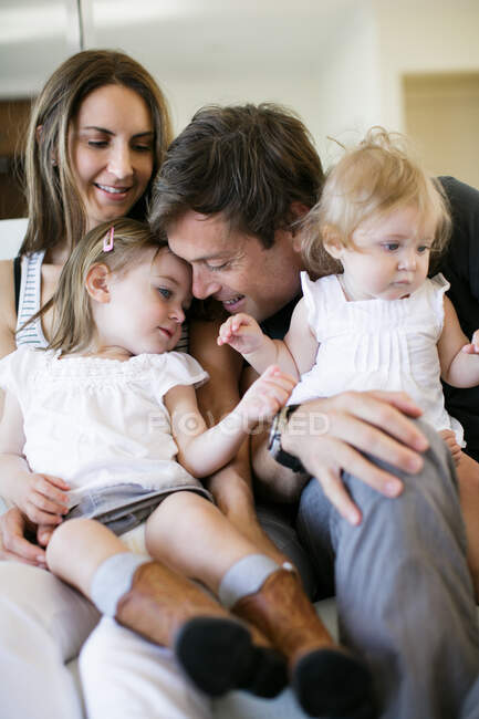 Couple adulte moyen avec bébé et filles tout-petits sur les genoux — Photo de stock