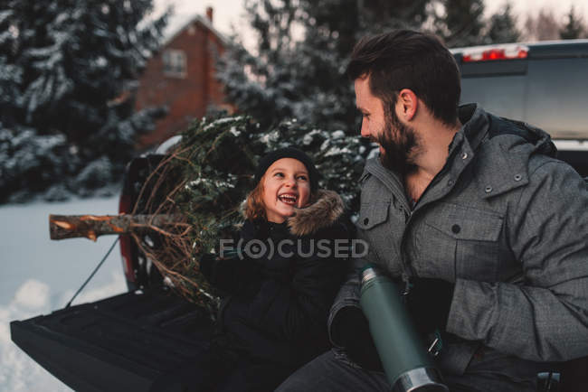 Padre e hija en la parte trasera de la camioneta con su árbol de Navidad - foto de stock