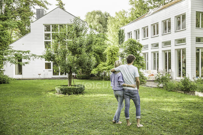 Vue arrière du couple flânant dans un jardin verdoyant — Photo de stock