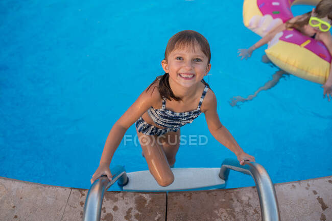 Portrait of young girl climbing out of swimming pool — Stock Photo