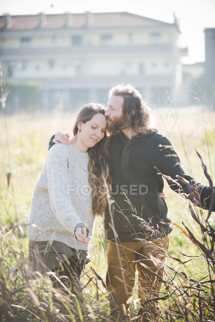 Junges Paar trägt berührende Pflanzen auf Feld — Stockfoto