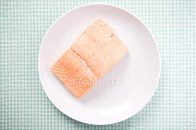 Plate with salmon fillet on checkered tablecloth — Stock Photo