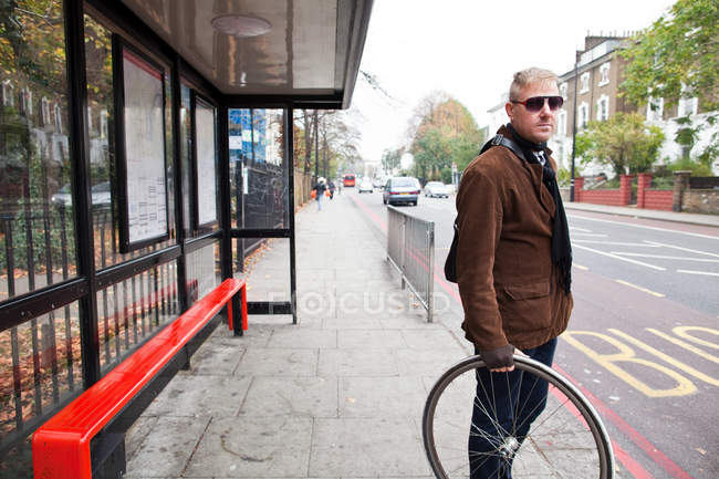 Radfahrer wartet an Bushaltestelle — Stockfoto