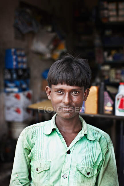 Smiling man sitting in front of shop — Stock Photo