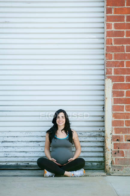 Pregnant young woman sitting cross legged, portrait — Stock Photo