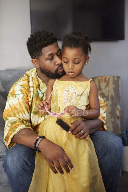 Man on sofa with daughter in princess costume — Stock Photo