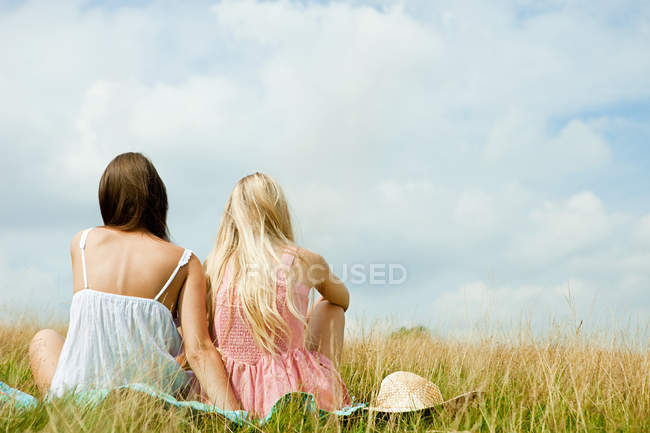 Joven pareja de lesbianas sentados juntos en el campo - foto de stock