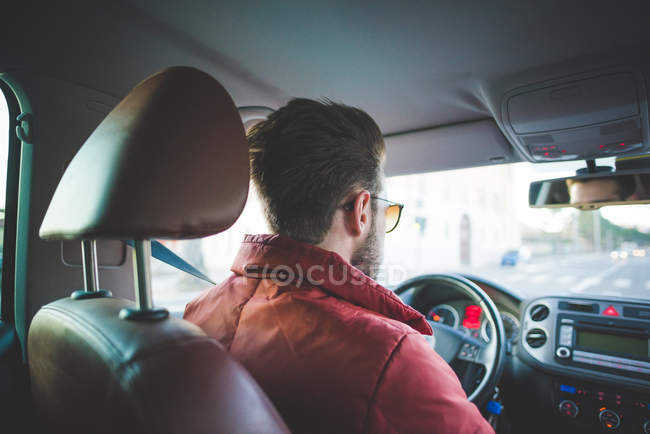Вид сзади на молодого человека на дороге за рулем автомобиля — стоковое фото
