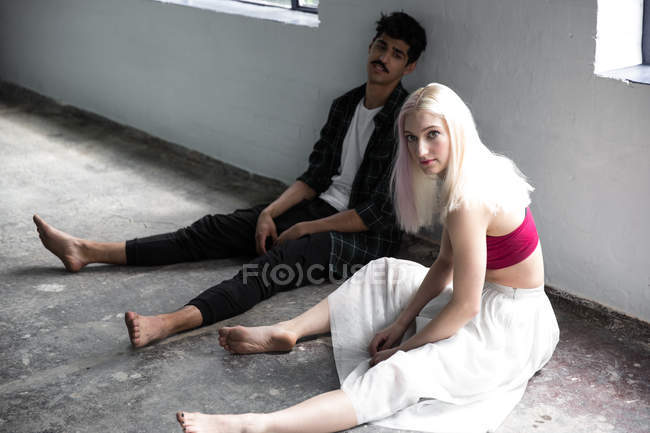 Танцоры отдыхают и сидят на полу в студии — стоковое фото