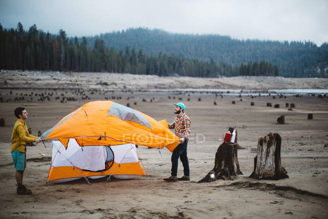Due giovani uomini piantano una tenda sulla spiaggia, Huntington Lake, California, USA — Foto stock
