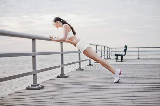 Woman doing push ups on wooden dock — Stock Photo